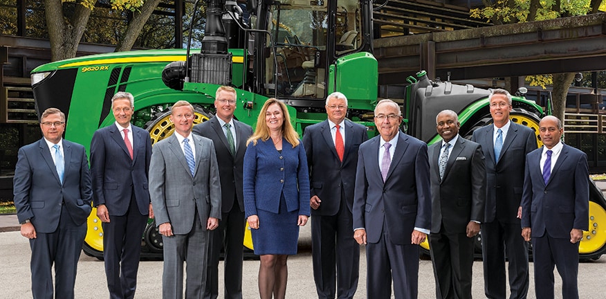 Руководство компании John Deere изображено на здании правления корпорации с трактором на заднем фоне.