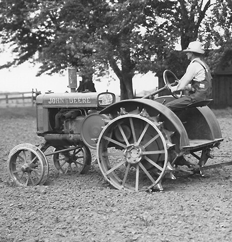 Исторический трактор общего назначения John Deere тянет в поле фрезерный культиватор John Deere № 7