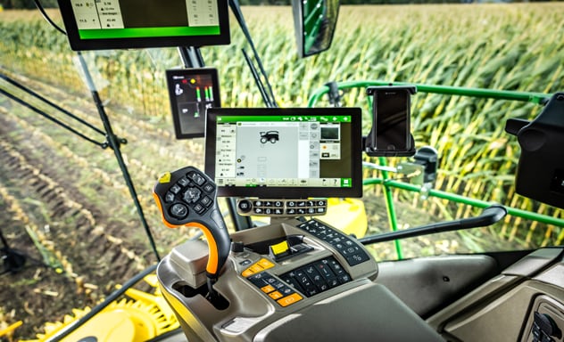 Самохідний кормозбиральний комбайн F9 700 завантажує причіп Joskin, що тягнеться трактором 6R John Deere